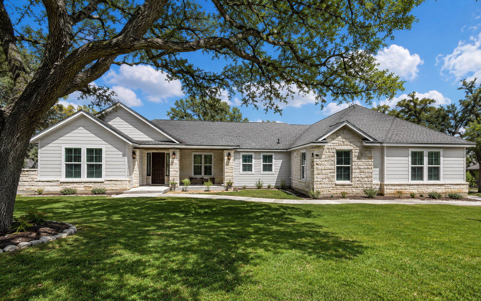 Finished Texas limestone and siding home under live oaks